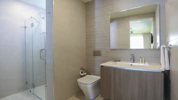 Un baño moderno con cabina de ducha de vidrio, inodoro y tocador con espejo.
