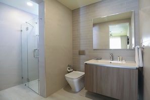 Un baño moderno con cabina de ducha de vidrio, inodoro y tocador con espejo.