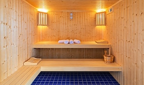 Una sauna con paredes de madera, un banco, un banco con toallas y un cubo de madera.