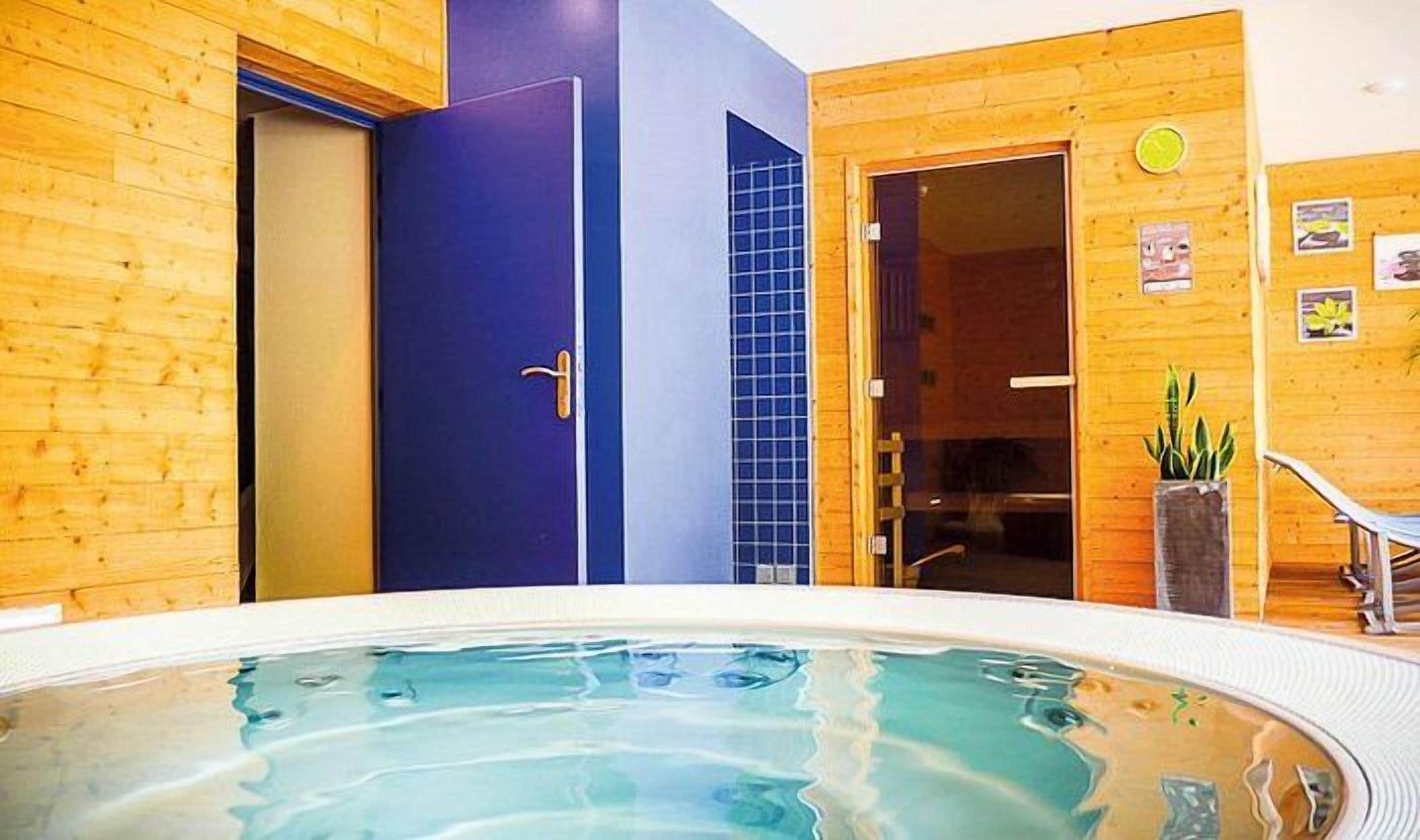 Un interior de madera con un jacuzzi, una puerta azul y un revestimiento de azulejos.