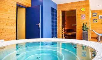 Una piscina interior moderna con revestimiento de madera, una puerta azul y un reloj en la pared.