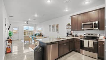 A modern kitchen with stainless steel appliances, wooden cabinets, and a large island with a dishwasher.