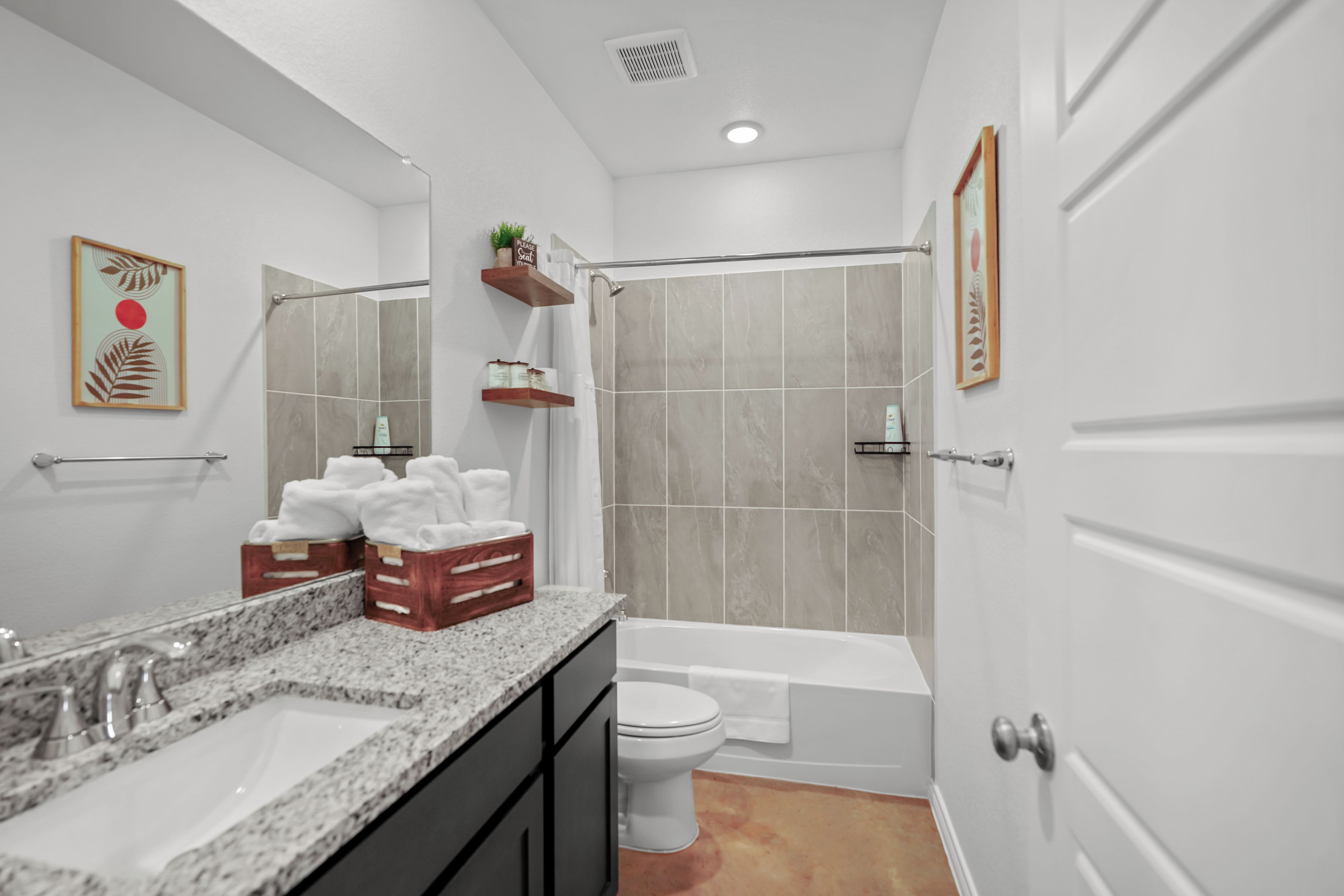 A modern bathroom with a bathtub, toilet, and sink. There are towels and toiletries on the counter.