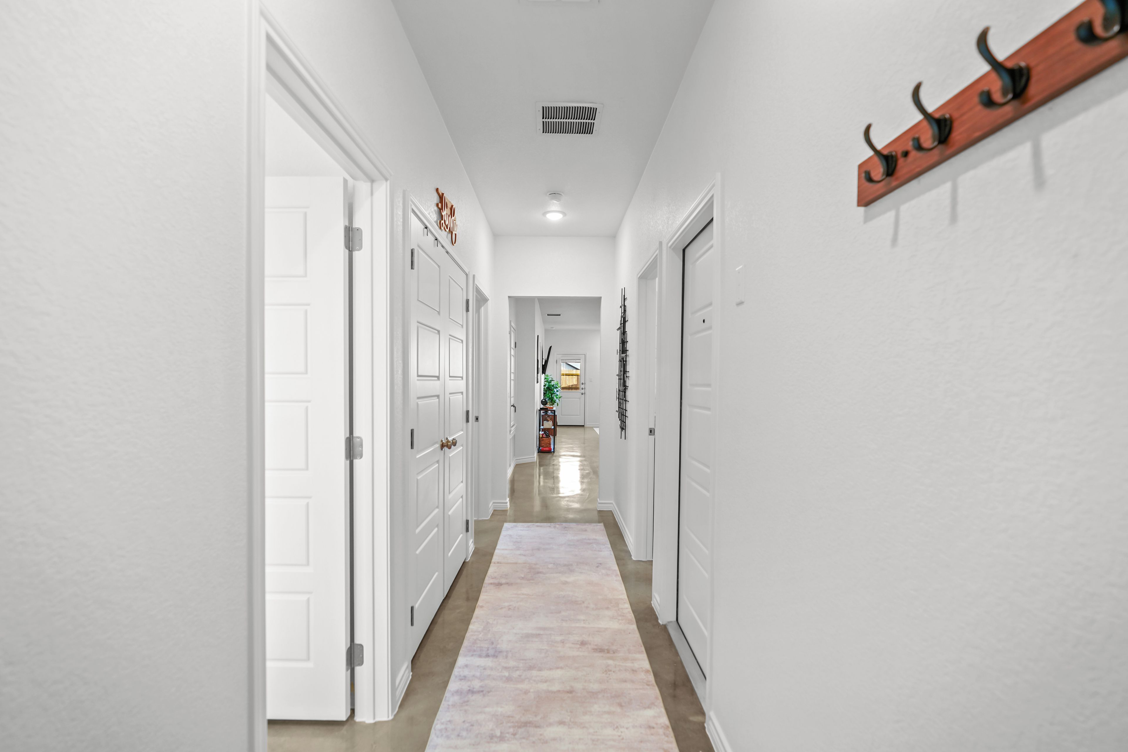 A hallway with white doors, a wooden coat rack, and a light-colored carpet.