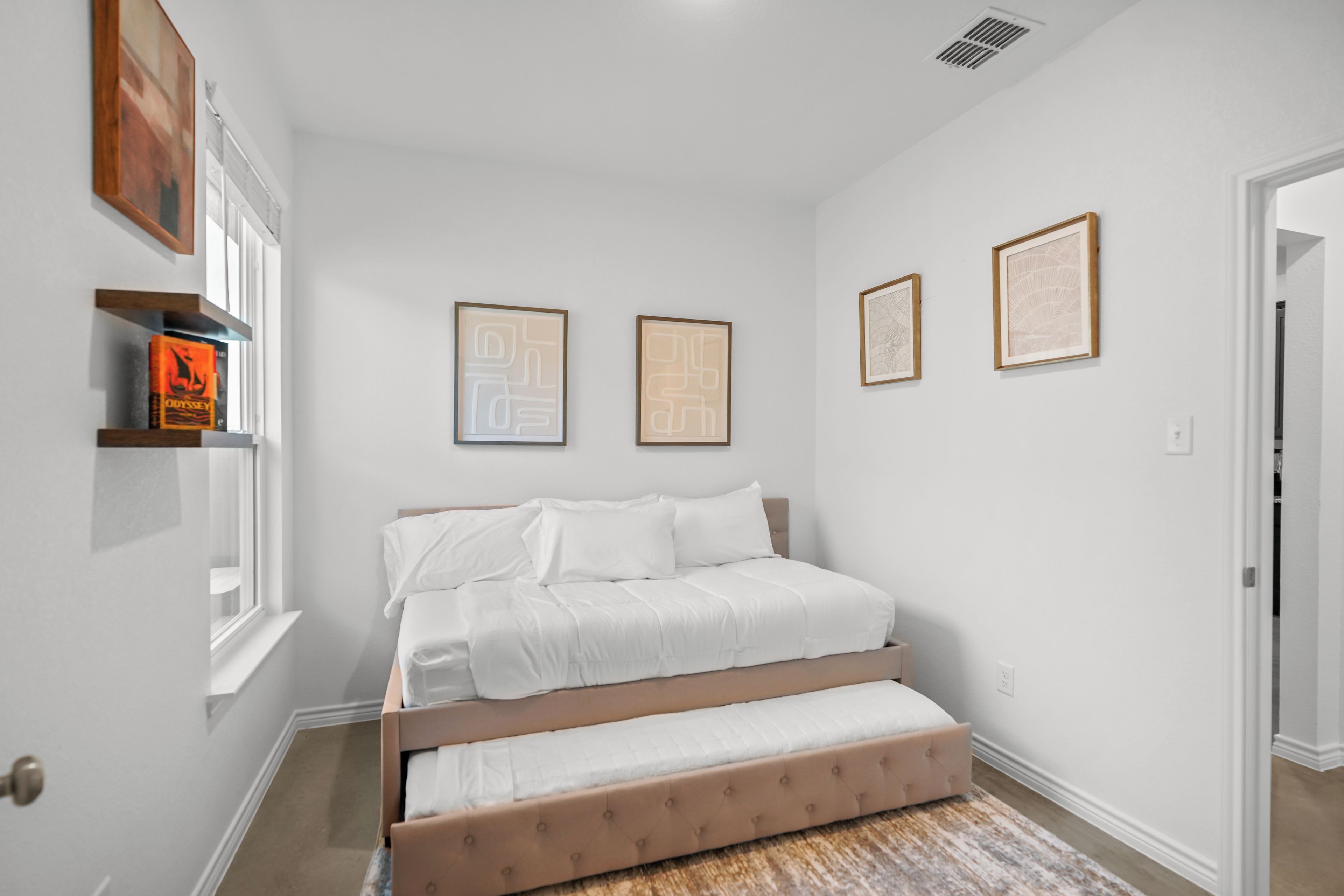 Camera da letto con un letto, una finestra e opere d'arte appese al muro.