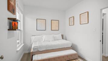 Camera da letto con un letto, una finestra e opere d'arte appese al muro.