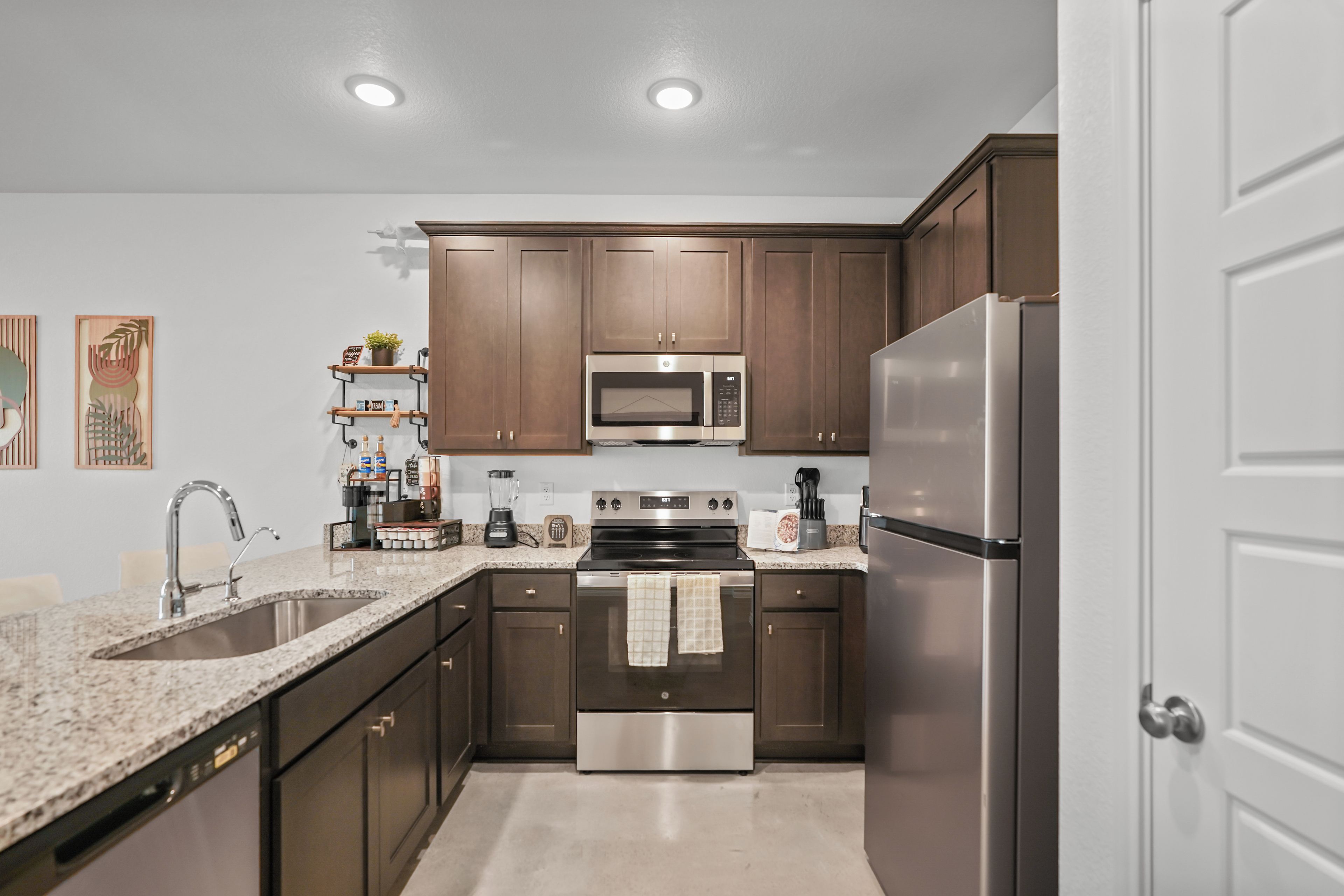 Una cocina moderna con electrodomésticos de acero inoxidable, armarios de madera y encimera de granito.