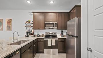 Una cocina moderna con electrodomésticos de acero inoxidable, armarios de madera y encimera de granito.