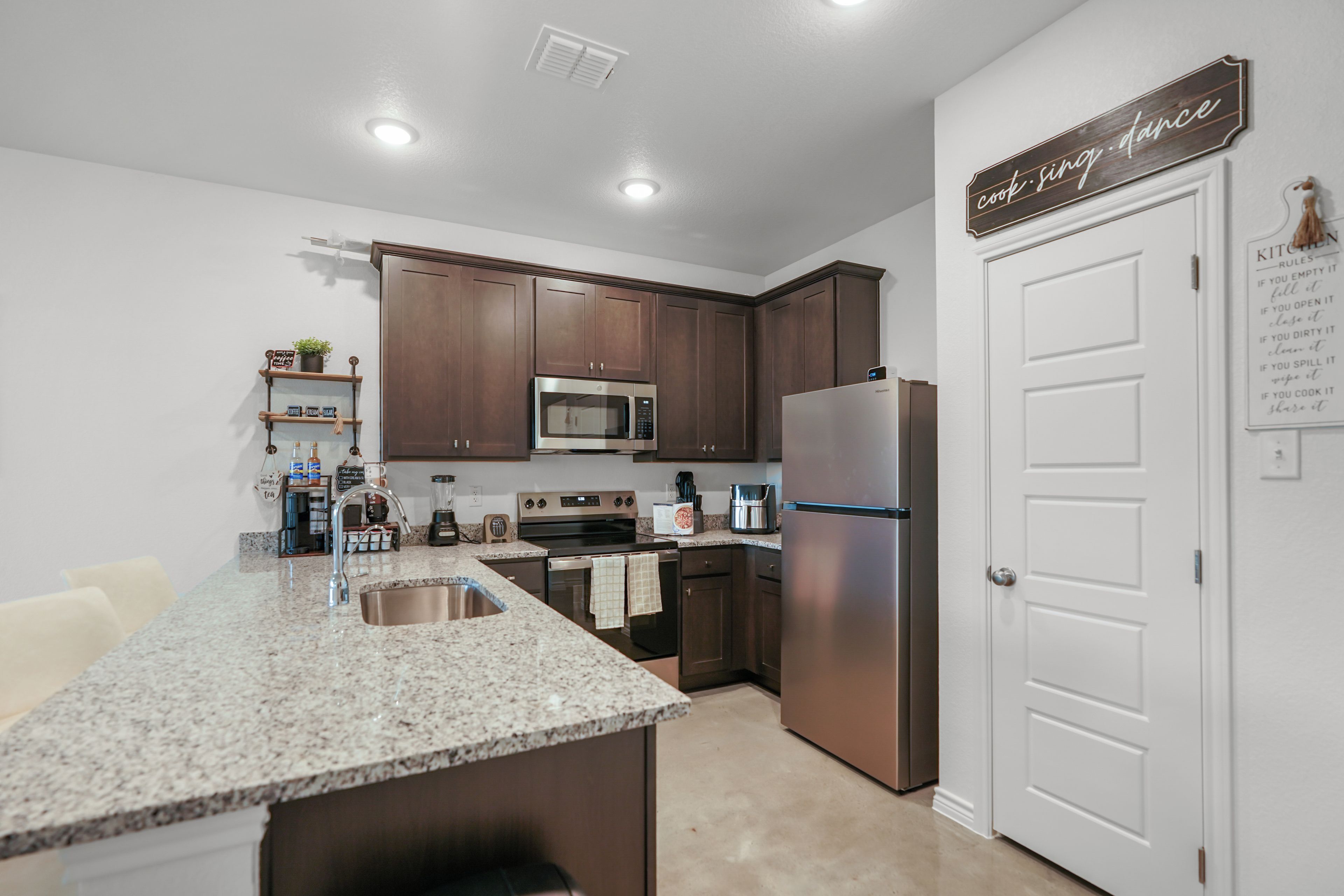 A modern kitchen with granite countertops, stainless steel appliances, and wooden cabinets.
