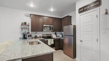 A modern kitchen with granite countertops, stainless steel appliances, and wooden cabinets.