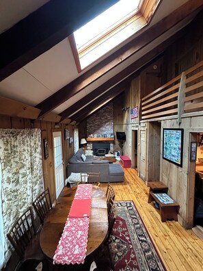 Een gezellig chaletinterieur met een eethoek, een bank en een open haard.