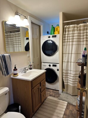 Een badkamer met een wastafel, spiegel, toilet en een gestapelde wasmachine-droger combinatie.