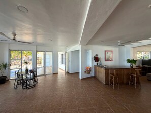 A spacious living area with a kitchen, dining table, and bar area. - A genuine Yucatecan Summer House by the Sea (Chicxulub)