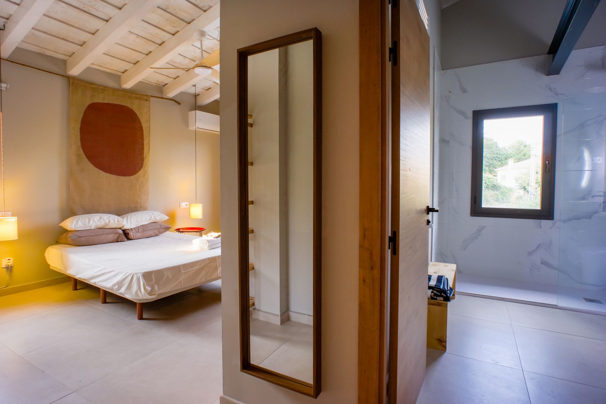 Une chambre à coucher avec un lit, des lampes de chevet et un grand miroir.