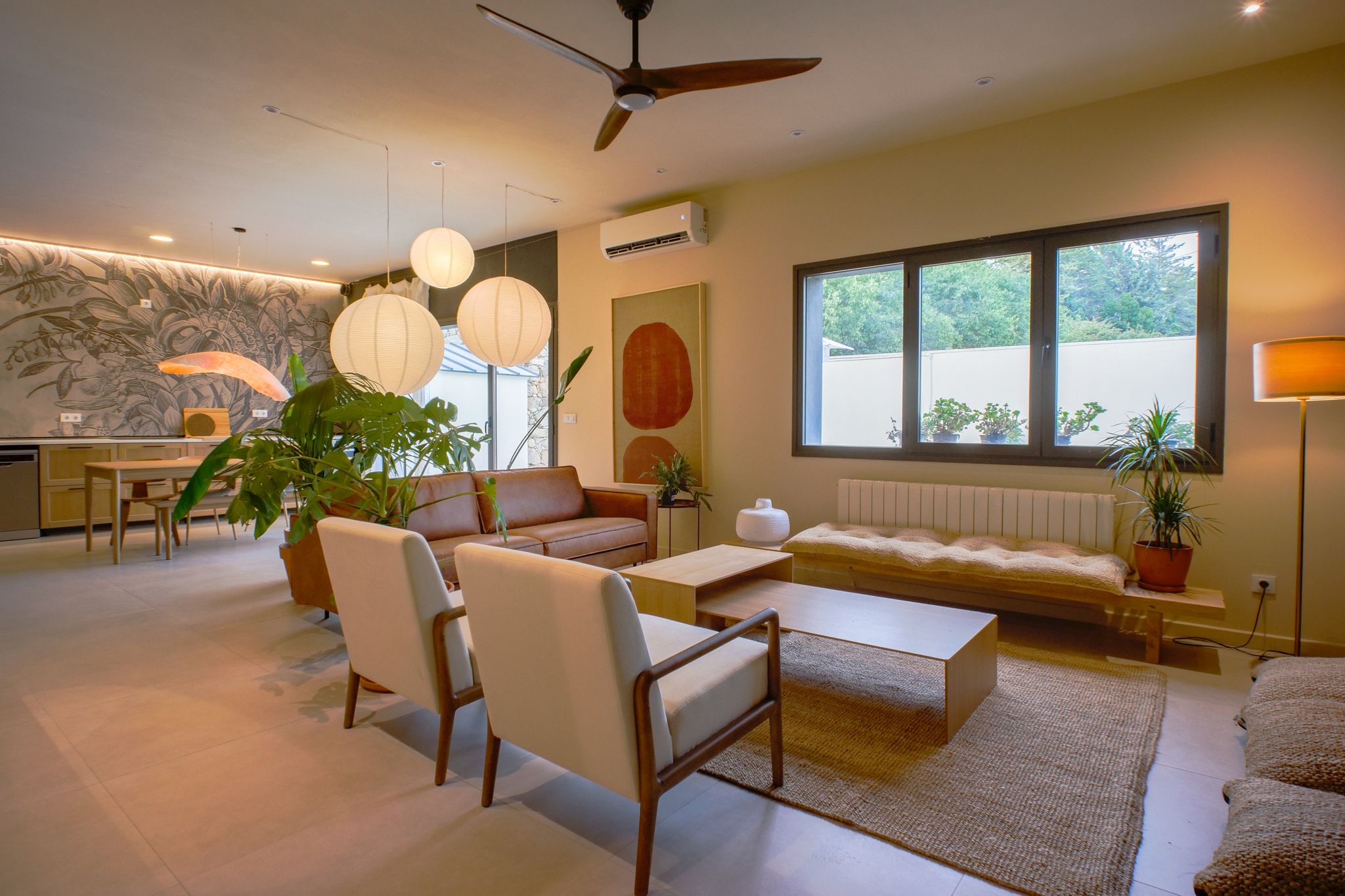 Un salon moderne comprenant un canapé, des fauteuils, une table basse et un coin repas avec une table et des chaises.