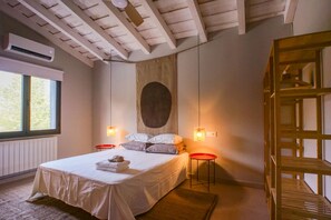 A bedroom with a bed, bedside tables, a window, and a wall-mounted air conditioner.