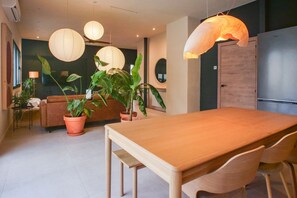 A modern dining area with a wooden table and chairs, surrounded by potted plants and hanging paper lanterns. - Detached house with a garden and pool in Candeleda: Casa Vettonia (Candeleda)