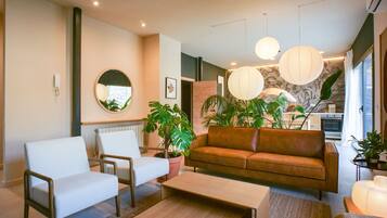 Un salon moderne avec un canapé, des fauteuils, une table basse et des plantes en pot.