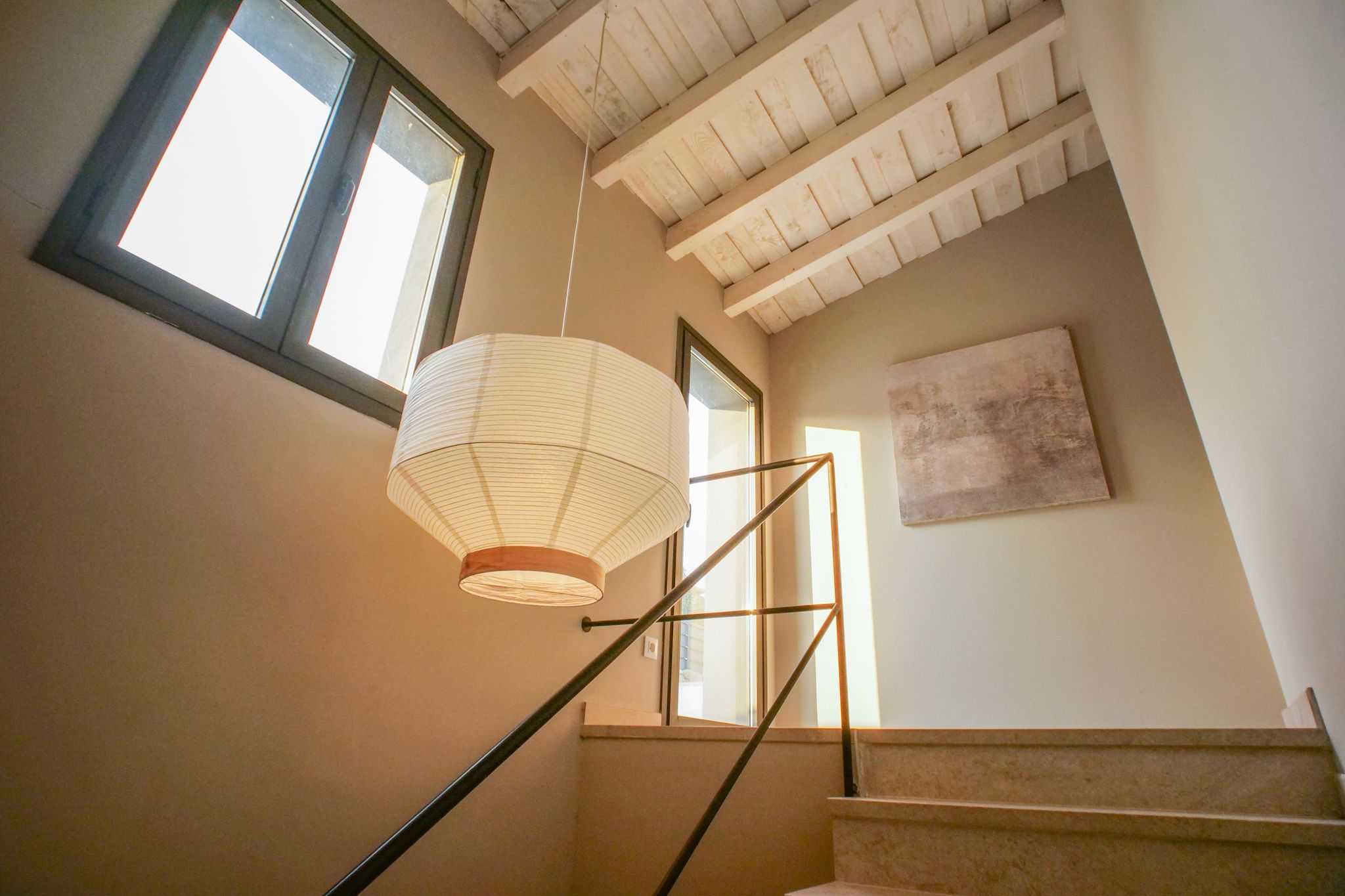 Un escalier avec un luminaire suspendu et un tableau accroché au mur.