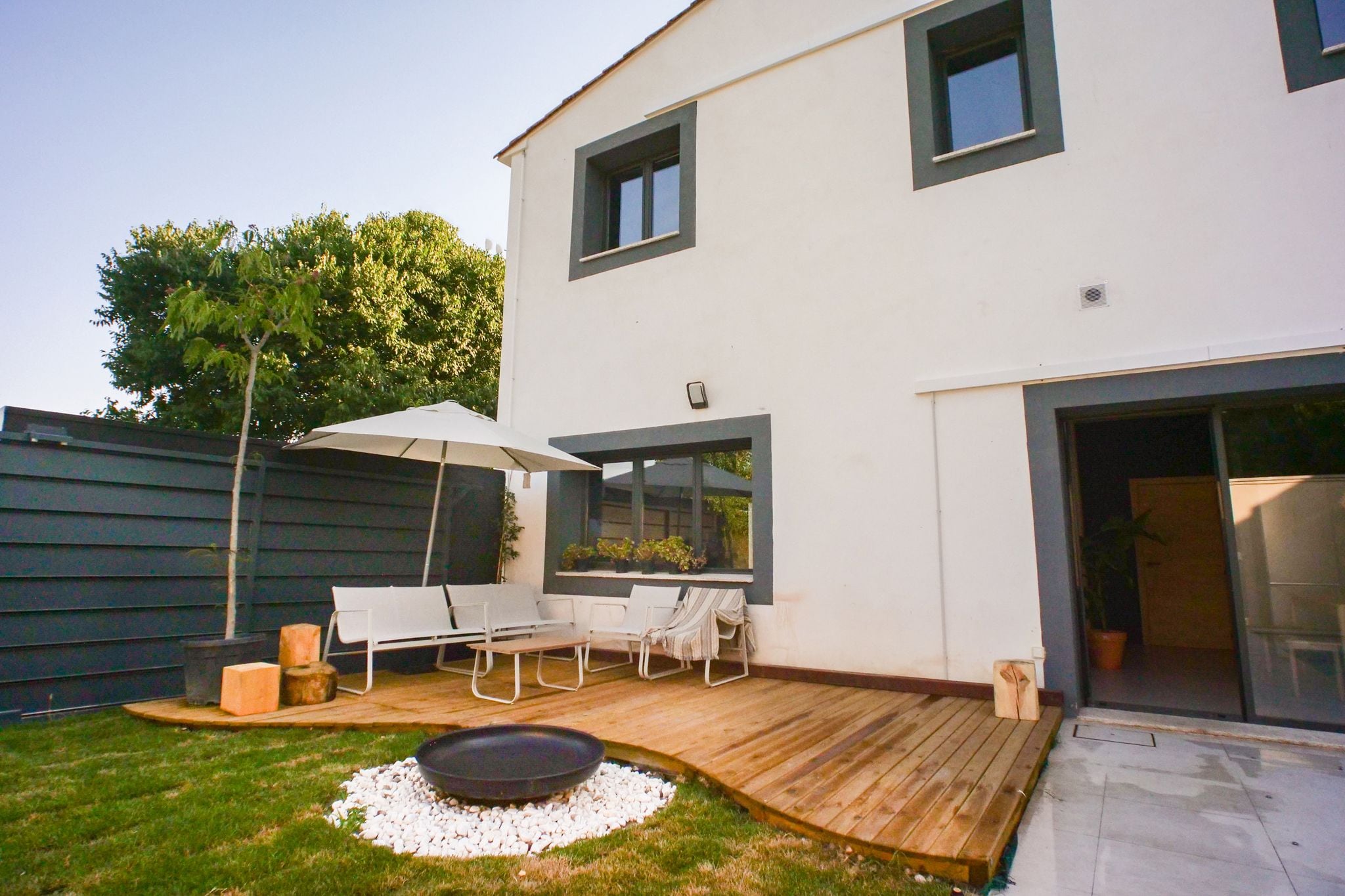 Une maison moderne dotée d’un patio, d’un espace salon extérieur et d’un foyer.