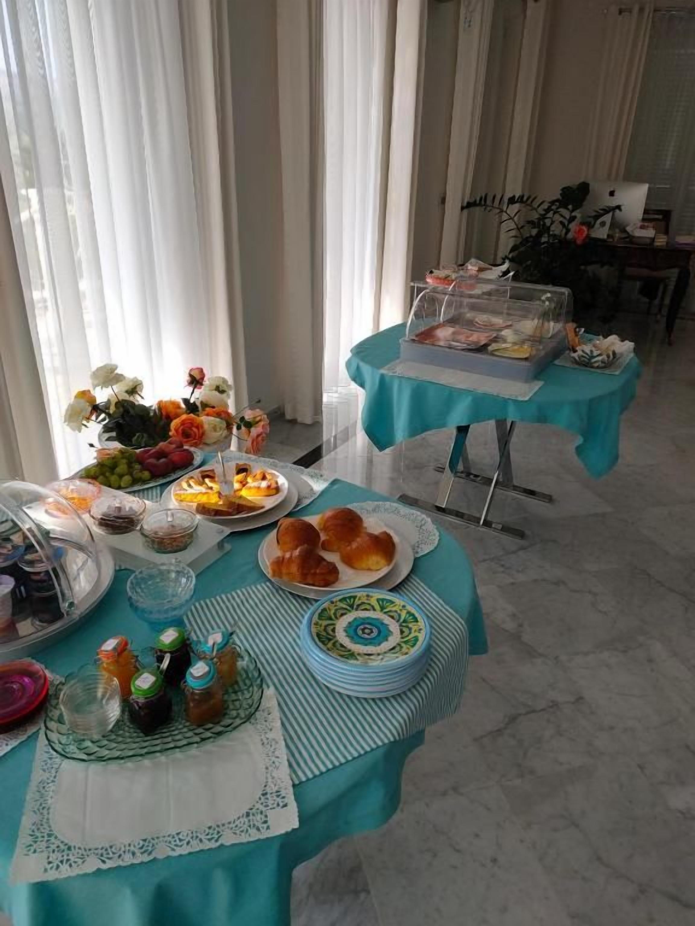 Un bufé de desayuno con diversos alimentos y una computadora portátil sobre una mesa.