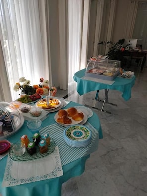 Un esmorzar tipus buffet amb diferents aliments i un ordinador portàtil sobre una taula.