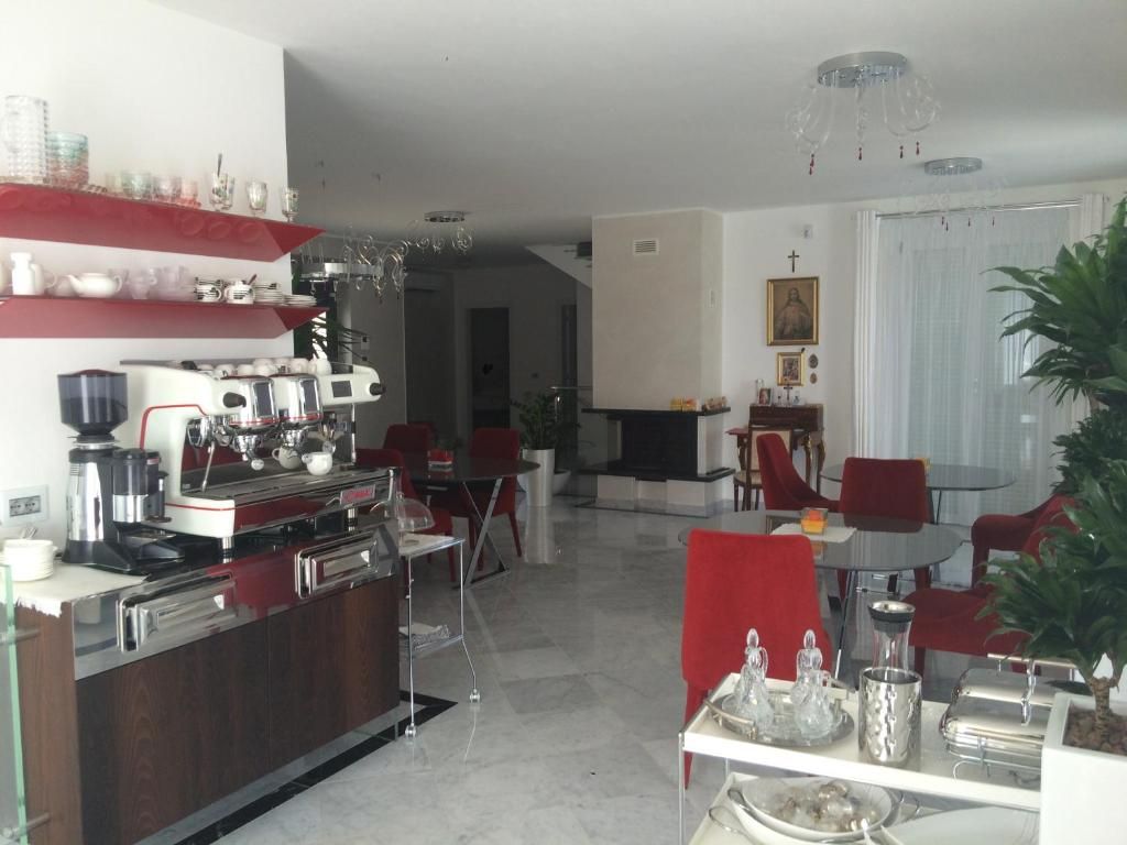 Una cocina moderna con cafetera, una zona de comedor con sillas rojas y una chimenea.