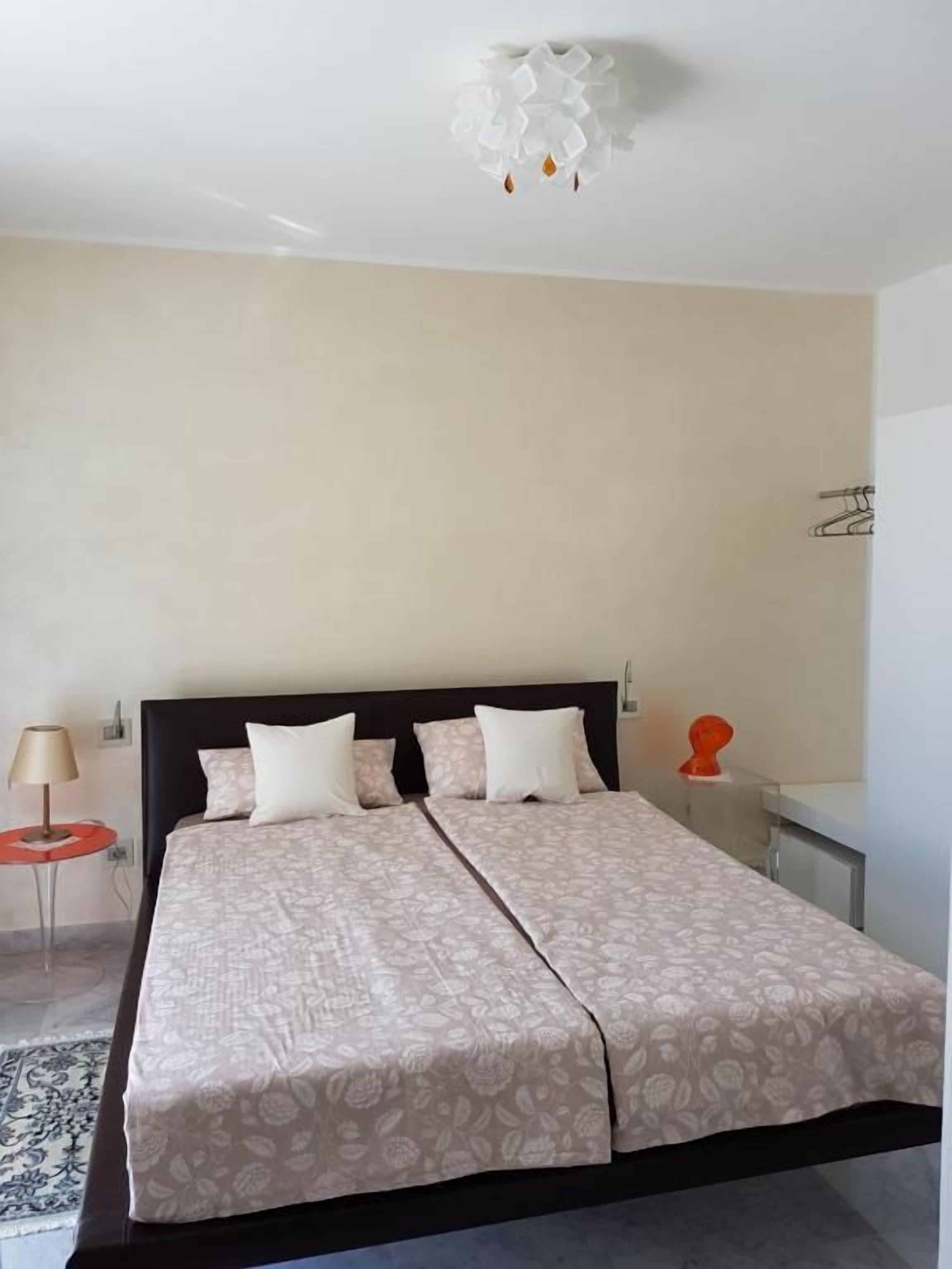 Un lit double avec une couvre-lit à motifs, une table de chevet avec une lampe et un porte-serviettes fixé au mur.