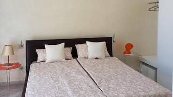 Un lit double avec une couvre-lit à motifs, une table de chevet avec une lampe et un porte-serviettes fixé au mur.
