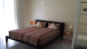 Una cama con colcha estampada, una mesita de noche con lámpara y una silla.