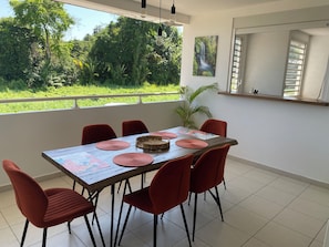 A dining area with a table set for six, red chairs, a large window with a view of greenery, and a hanging light fixture. - Just like at home!! A quiet and pleasant apartment with a balcony overlooking the forest (none)