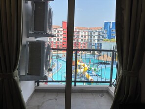 A view of a swimming pool with slides, surrounded by multi-story buildings with balconies.