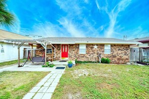 A residential house with a red door, a brick facade, and a small front yard with a swing set. - Joys Beach House (Panama City Beach)