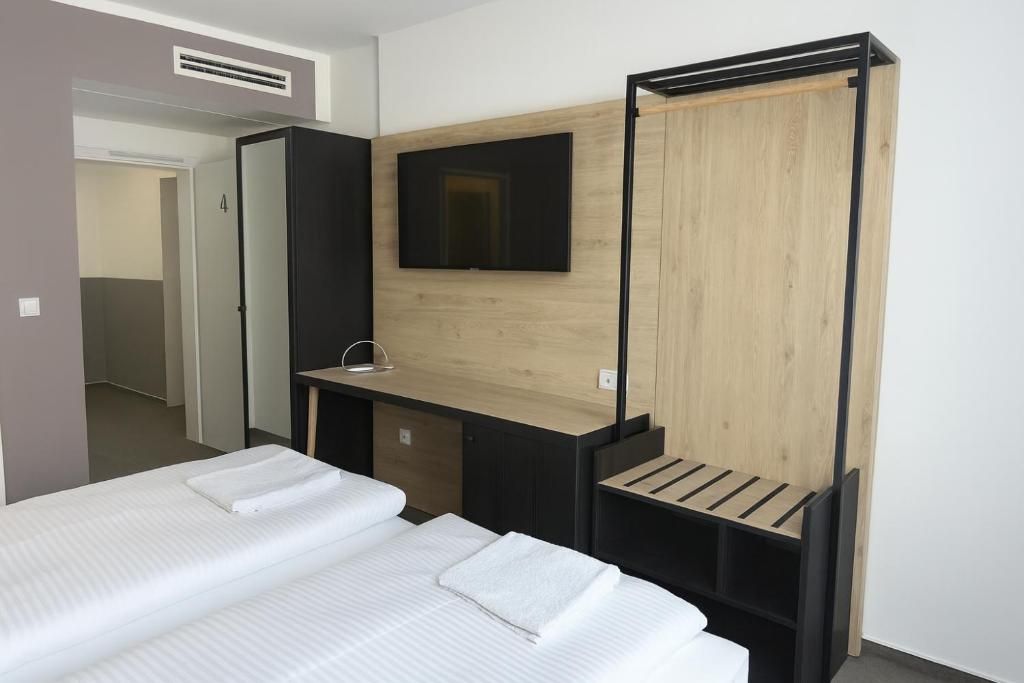 Ein modernes Hotelzimmer mit Bett, Schreibtisch, Fernseher und Kleiderschrank.