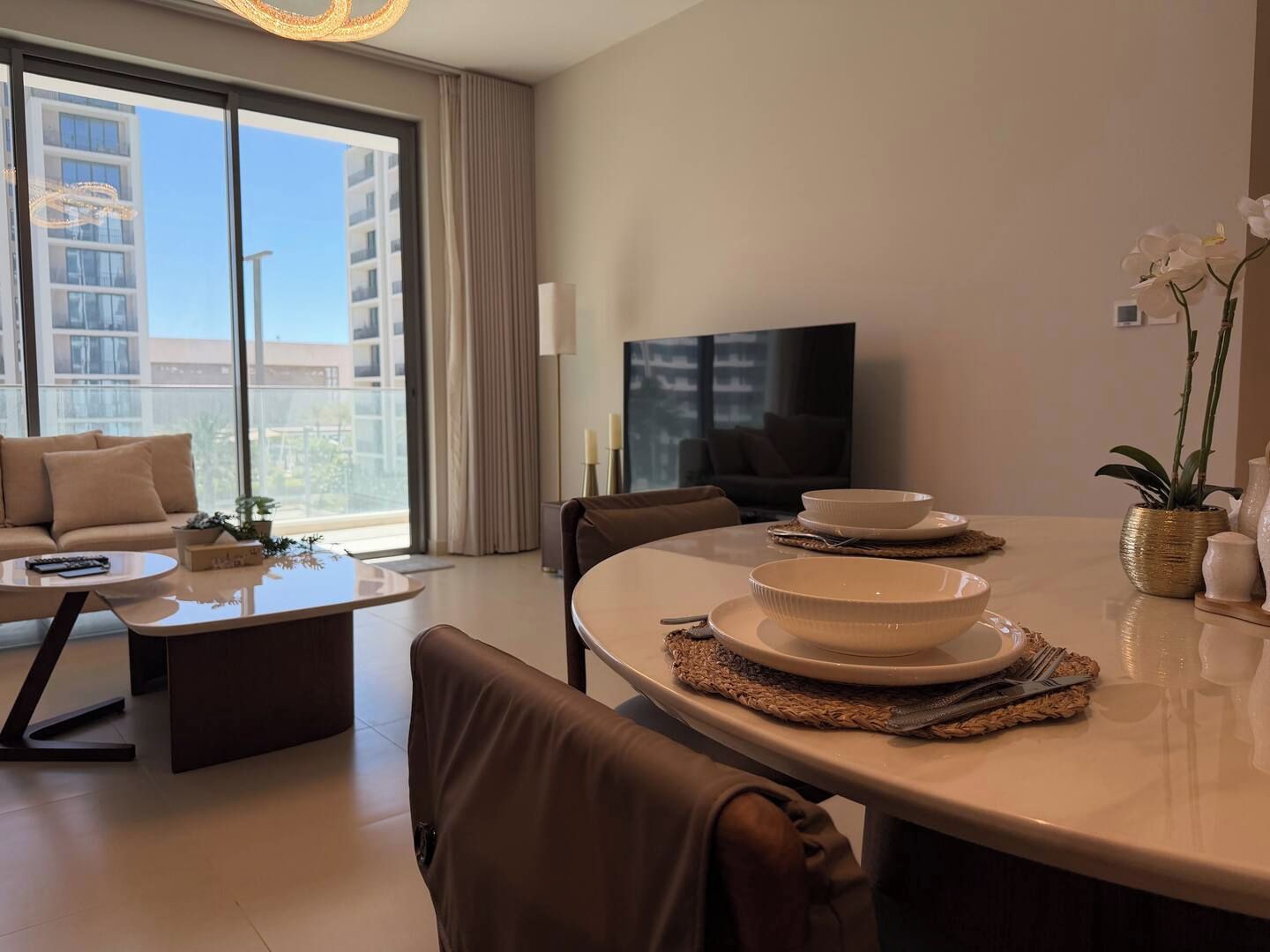 Una sala moderna con sofá, mesa de centro, mesa de comedor y televisor.