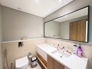 Un baño moderno con inodoro, bidé, tocador con lavabo y un espejo grande.