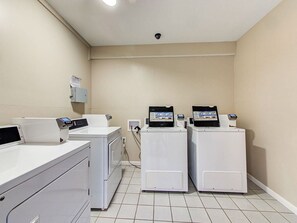 A laundry area with two washing machines, a dryer, and a control panel. - Golden Sunsets - 2 Bed, Pool, Beach, Fun (Gulf Shores)