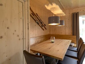 A wooden dining area with a table, chairs, and a hanging light fixture. - One-bedroom Cabin (Sankt Georgen am Kreischberg)