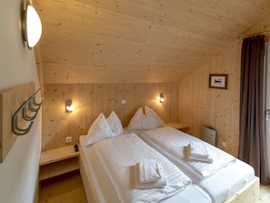 A wooden-paneled room with two beds, each with pillows and towels, and wall-mounted light fixtures. - One-bedroom Cabin (Sankt Georgen am Kreischberg)