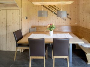 A wooden dining room with a bench, two chairs, a table, and a vase with flowers. - One-bedroom Cabin (Sankt Georgen am Kreischberg)