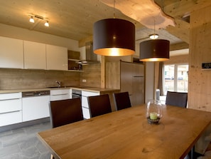 Eine moderne Küche mit weißen Schränken, einem Holztisch und Pendelleuchten.