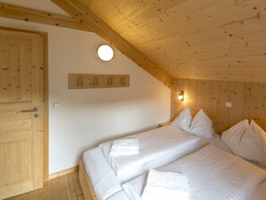 Ein Schlafzimmer mit Holzboden, einem Bett mit weißer Bettwäsche, einer Holztür und einer wandmontierten Lampe.