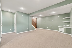 A spacious room with a carpeted floor, a staircase, and built-in shelves. - 4 King Beds Premium Home in Mason (Mason)