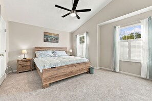 A bedroom with a bed, nightstands, a ceiling fan, a window with curtains, and a painting on the wall. - 4 King Beds Premium Home in Mason (Mason)