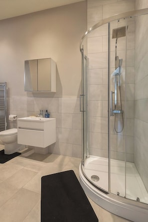 A modern bathroom with a glass-enclosed shower, a white vanity, and a toilet. - The Stylish Artist Penthouse | Central Harrogate (Harrogate)