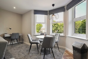 Een moderne eetruimte met een ronde tafel, grijze stoelen en een hanglamp.