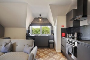 A compact kitchen with a built-in oven, a coffee maker, and a window overlooking greenery.
