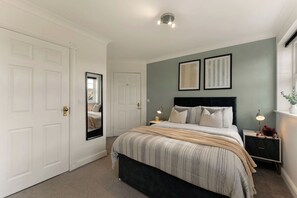A bedroom with a bed, bedside tables, a mirror, and a door. - The York Haven | Stylish 4-Bed Sleeps 10 (York)
