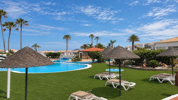 Ein Resort mit Swimmingpool, Liegestühlen und Palmen.