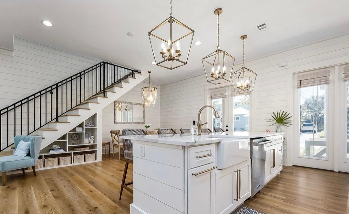 A modern kitchen with a central island, white cabinetry, and pendant lighting.